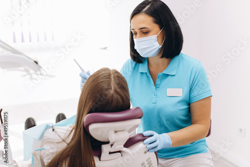 Female dentist examines her patient in a dental chair.