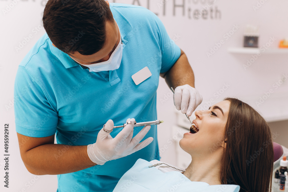 The dentist injects anesthesia to the girl patient, she is scared. The dentist injects anesthesia to the girl patient, she is scared.