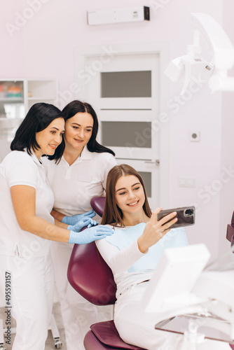 The girl in the dental office after the examination takes a selfie with dentists