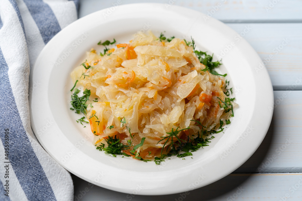 Plate of tasty stewed cabbage on wooden table