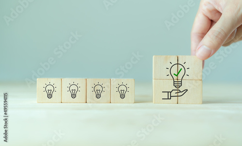 Suggestion and consulting concept. New idea, solution. Putting wooden cubes with light bulb on hand icon on beuatiful grey background and copy space. Business review, strategy suggestion for busines