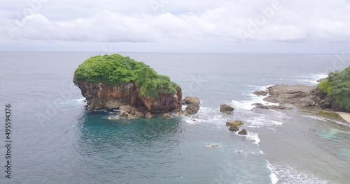 the sea water looks blue with some small rocks visible. Bird's eye view of the ocean. top view of waves breaking on rocks. shot from a distance then approached photo