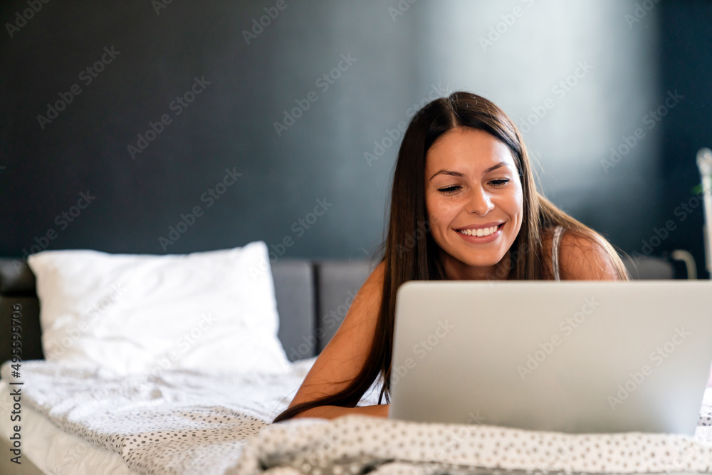 Beautiful woman working, studying with laptop on bed at home