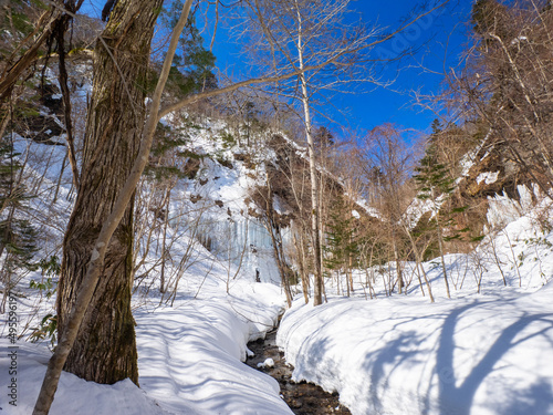 Icefalls seen beyond a snow-covered stream (Shiraoi, Hokkaido, Japan) photo