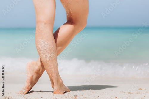 Holiday concept. Woman feet close-up relaxing on beach, enjoying sun and splendid view