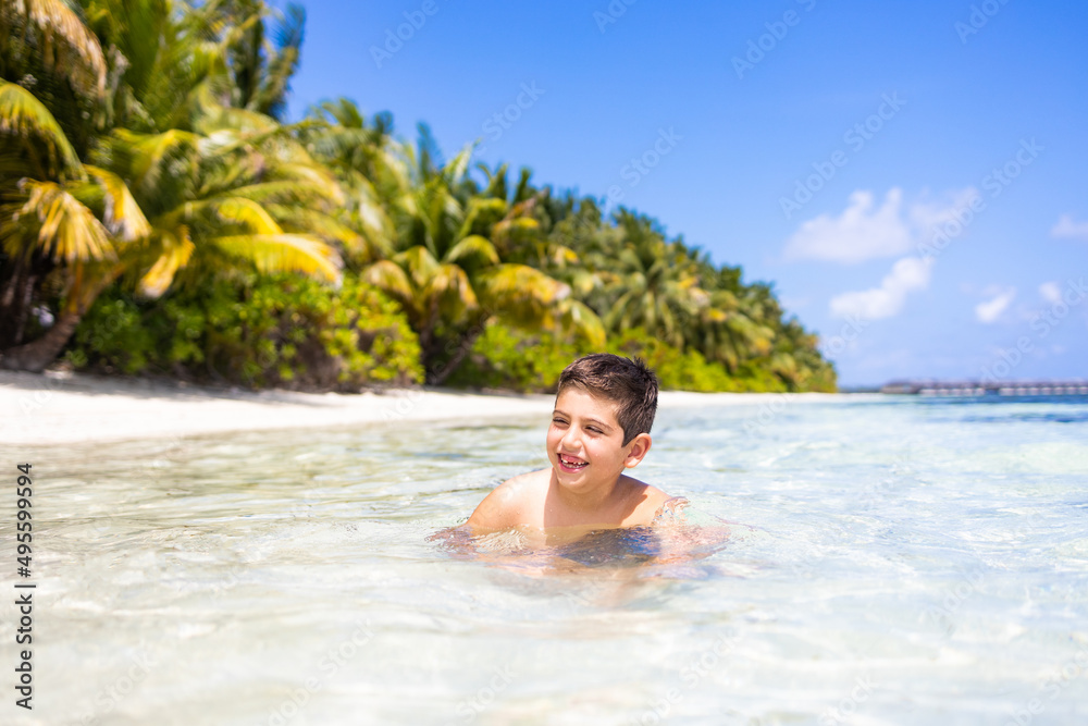 Little kid inside the water on a tropical beach
