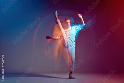 Fototapeta Naklejka Na Ścianę i Meble -  Dancing fighting energetic young sport girl training kicking, stretching legs performing freestyle dance. Long exposure