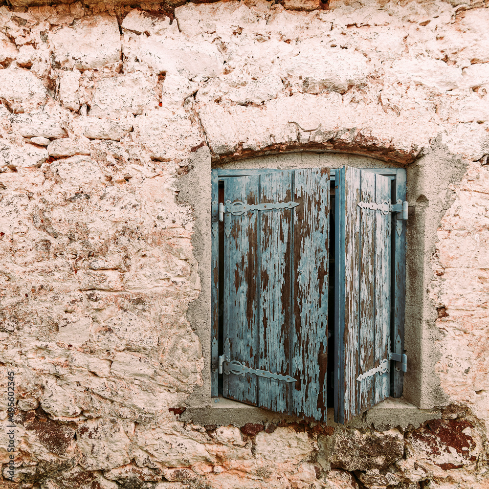 A lonely window with closed shutters on the rough wall of an old stone house. Pachia Rachi, Aegina, Greece. A lonely window with closed shutters on the rough wall of an old stone house. Pachia Rachi, Aegina, Greece.
