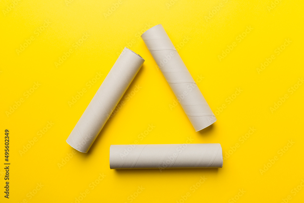 Empty toilet paper roll on colored background. Recyclable paper tube with metal plug end made of kraft paper or cardboard in the form of a recycling sign Empty toilet paper roll on colored background. Recyclable paper tube with metal plug end made of kraft paper or cardboard in the form of a recycling sign
