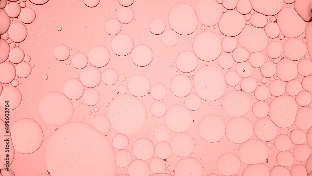 Different sized oil bubbles float in clear liquid against coral color background | Abstract skin care product formulating concept. Background for beauty products.