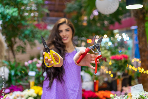 A beautiful florist shows a pair of scissors she works with while making bouquets