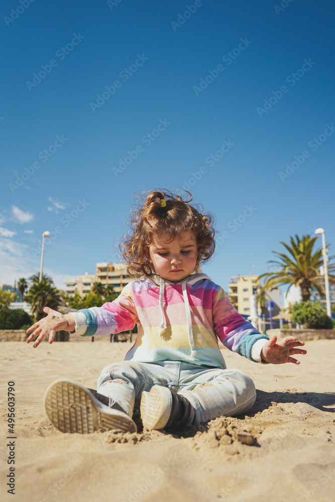 Young toddler playing with the sand at the beach Young toddler playing with the sand at the beach