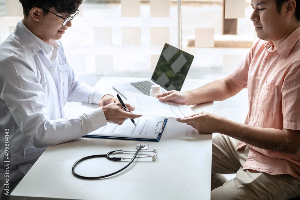 Fototapeta premium Male doctor discussing with the patient explaining symptoms of the disease after diagnosis checking while recommending treatment methods in clinic
