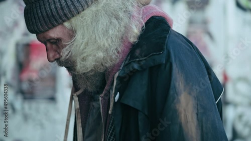 Anxious homeless male walking in deprived area, sitting on bench, looking around