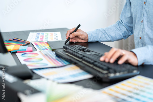 Young creative graphic designer working on color selection and drawing on graphics tablet at workplace, Color swatch samples chart for selection coloring
