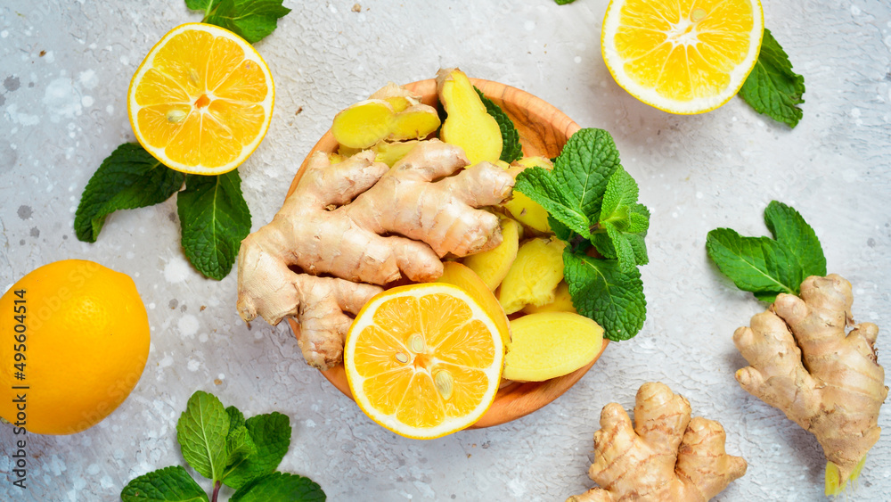 Sliced ginger and lemon slices in a wooden plate. Side view. On a stone background. Sliced ginger and lemon slices in a wooden plate. Side view. On a stone background.