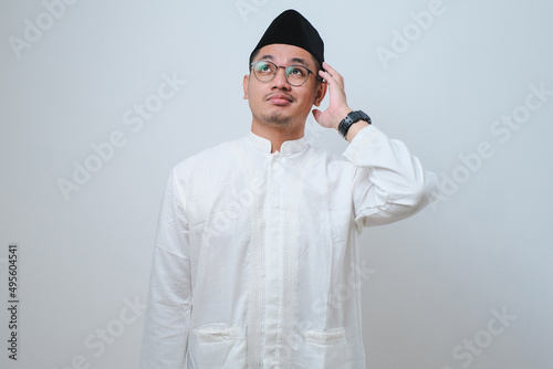 Asian muslim man doing thinking gestire, looking for idea photo