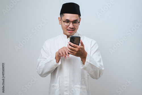 Happy asian muslim man holding and pointing on phone cellular