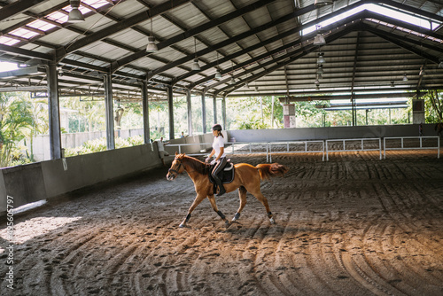 Obraz na płótnie Young woman trains in horseback riding in the arena