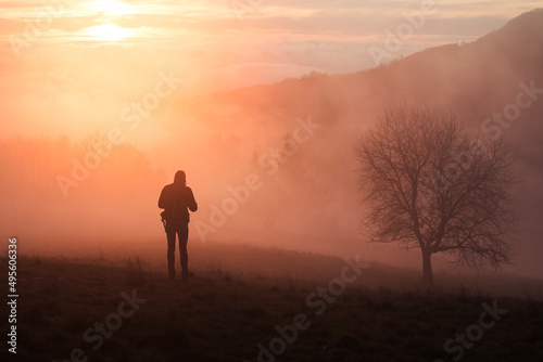 silhouette of a person standing on a mountain at sunset