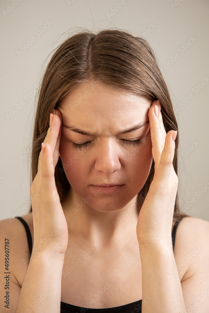 young female suffers from headache migraine holding hands near temple head young female suffers from headache migraine holding hands near temple head