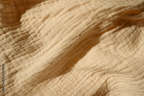 Diagonal soft fold on thin beige cotton muslin fabric
