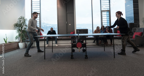 Young start up business man and woman playing table tennis at modern creative office space people group have meeting and brainstorming in background © .shock