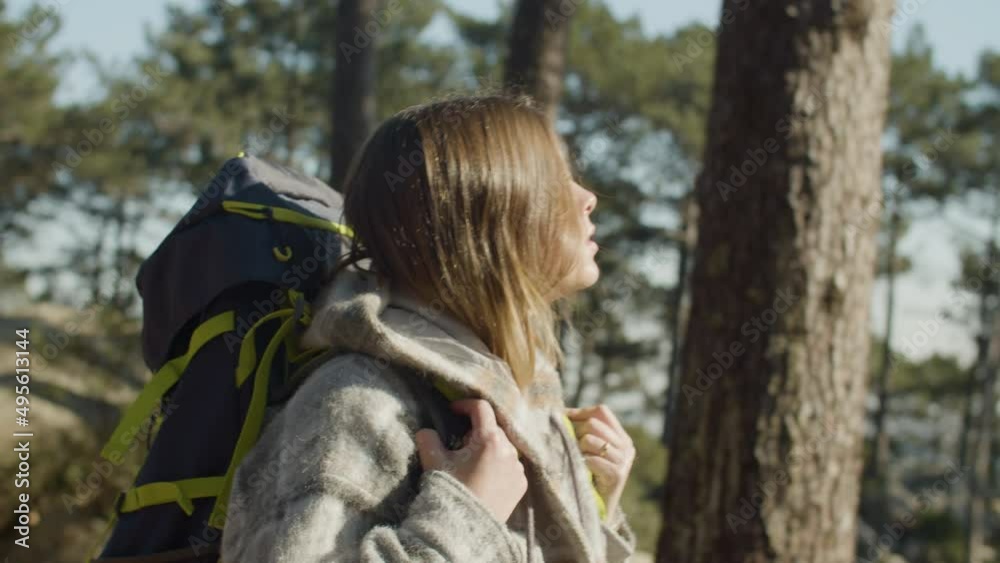 Active Caucasian woman enjoying hiking trip in forest on sunny autumn day, walking alone and carrying backpack. Long-haired girl looking around, amazed with nature beauty. Backpacking, nature concept Active Caucasian woman enjoying hiking trip in forest on sunny autumn day, walking alone and carrying backpack. Long-haired girl looking around, amazed with nature beauty. Backpacking, nature concept