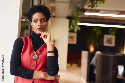 Portrait of mature black woman with hand on chin looking at camera with a pensive expression in coworking space photo