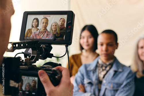 Videographer filming group of multiethnic women for International Women's Day with digital image on camera screen