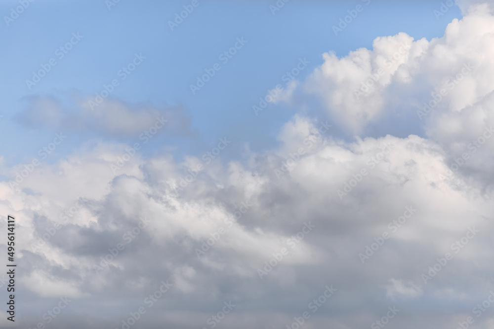 Aggressive looking grey-white big cumulus cloud on a morning soft blue sky background
