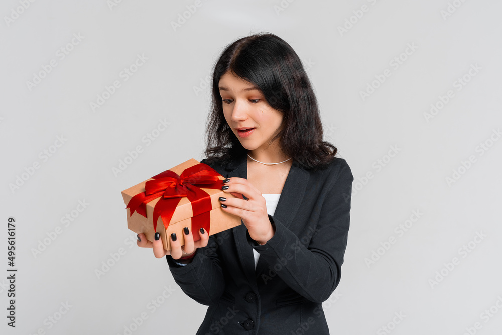 Curious cute brunette teenager girl in black blazer celebrating birthday, wonder whats inside b-day gift, opening box and smiling happy, grey background. lucky person Curious cute brunette teenager girl in black blazer celebrating birthday, wonder whats inside b-day gift, opening box and smiling happy, grey background. lucky person
