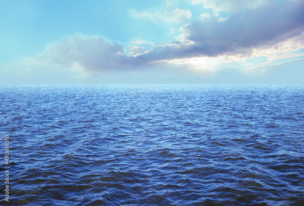 Fototapeta premium Beautiful deep azure blue sea and sky background - rich blue rippling ocean and ceruleum blue sky with beautiful cloud formation ideal for holiday travel cruise concept or spiritual theme message 