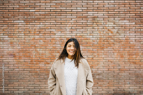 Portrait of a young smiling woman against a brick wall
