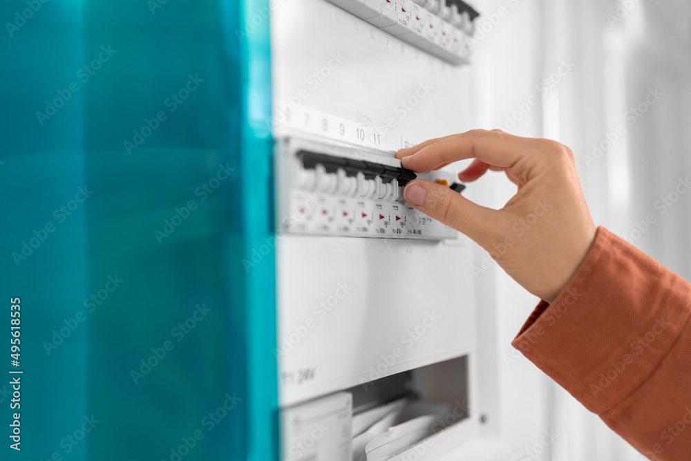 electricity, energy and power consumption concept - close up of hand switching electric board at home electricity, energy and power consumption concept - close up of hand switching electric board at home
