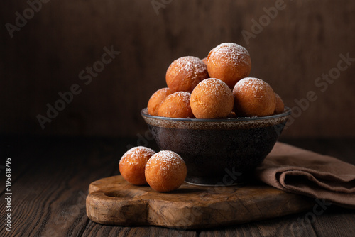 Homemade Donut Holes fried in oil until golden brown and sprinkled with sugar. Castagnole or Favette or Frittelle or Frittole is an Italian fried doughnut. Dark background. photo