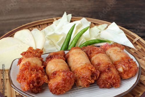 Isaan sausages, or fried sausages "sai krok isan". Tiny round sausage pork ball served in a plate with chili, ginger and fresh cabbage.