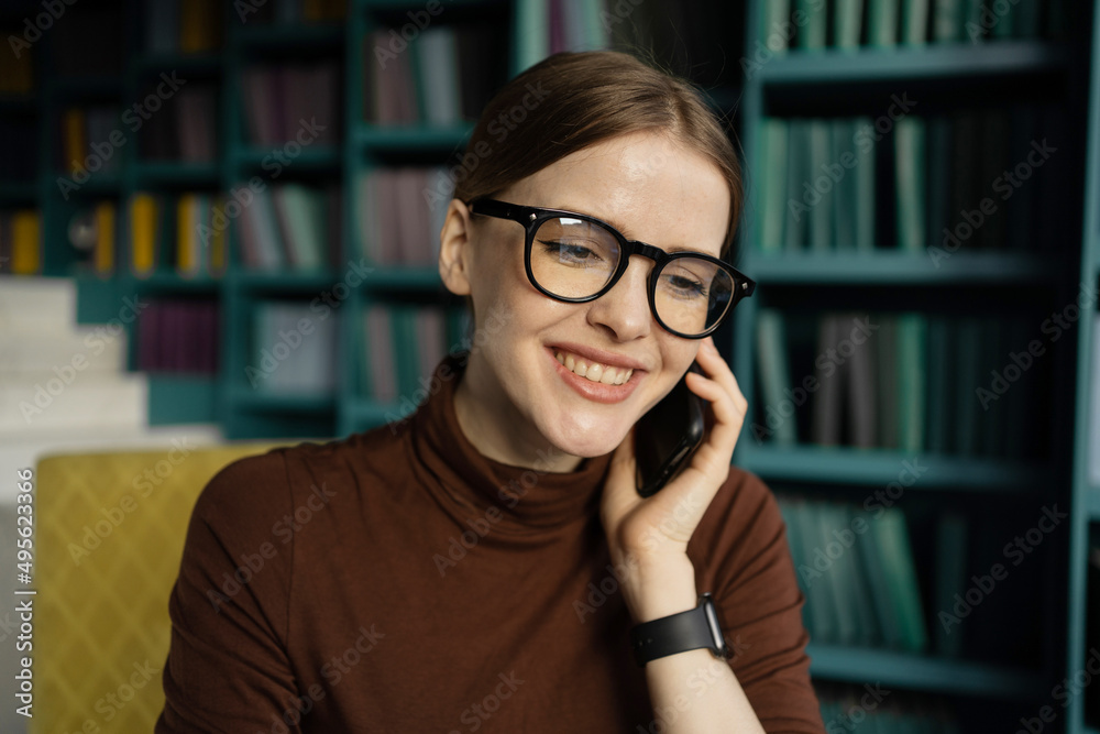 The manager is a woman with glasses talking on the phone with a client, working in the office The manager is a woman with glasses talking on the phone with a client, working in the office