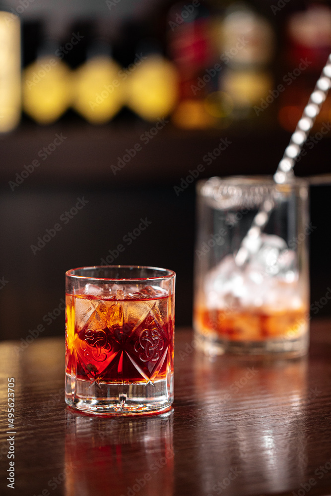 Crystal glass of classic negroni cocktail with bar tools