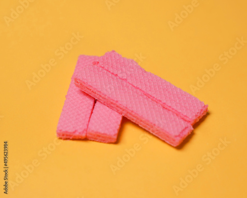 Stacks of pink wafers neatly arranged on a yellow background. Pile of taro flavored wafers. savory and crunchy snacks. snack. colorful wafers. food photography. delicious and delicious