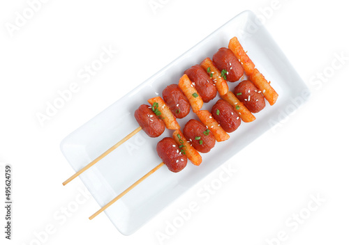 Close up of Sotteok, Skewered fried rice cakes and sausages topped with white sesame and green onion leaf on white plate with clipping path photo