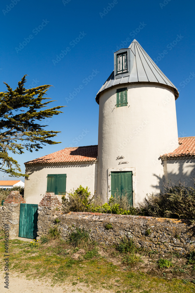 Vieux moulin restauré derrière un muret de pierres sèches, volets verts. La Court à Noirmoutier