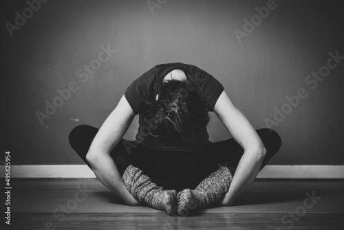 Grayscale shot of a young female practicing yin yoga in a studio