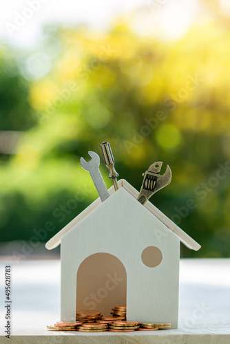 Home models, gold coins, construction equipment and spanners put on the wooden table. Financial planning to build or renovate a home, real estate loan concept.