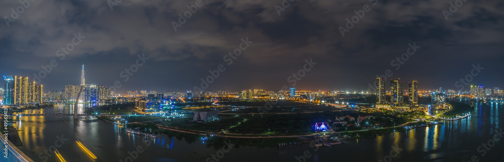 Fototapeta premium Aerial view of Bitexco Tower, buildings, roads, Thu Thiem 2 bridge and Saigon river in Ho Chi Minh city - Far away is Landmark 81 skyscrapper. This city is a popular tourist destination of Vietnam