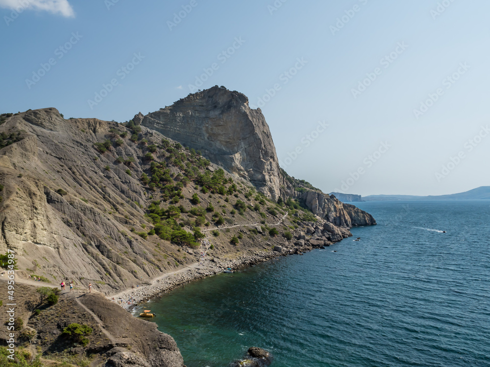 
Mountain landscape. View from the cape to the neighboring bald mountain. A large stone rock of sandy color with sparse bushes. Below the beach and the blue sea. Travelling around the world.