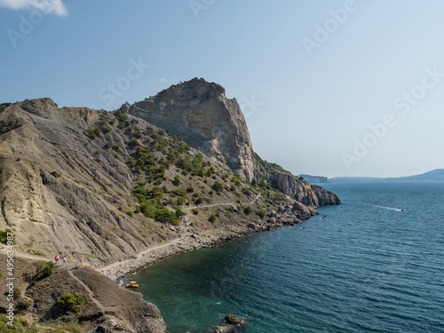  Mountain landscape. View from the cape to the neighboring bald mountain. A large stone rock of sandy color with sparse bushes. Below the beach and the blue sea. Travelling around the world.