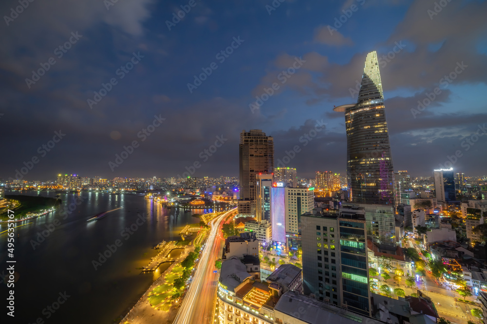 Fototapeta premium Aerial view of Bitexco Tower, buildings, roads, Thu Thiem 2 bridge and Saigon river in Ho Chi Minh city - Far away is Landmark 81 skyscrapper. This city is a popular tourist destination of Vietnam