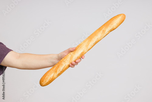 long bread baguette in a female hand on a white background close-up