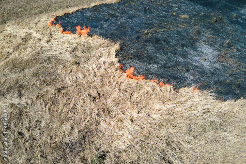 Aerial view of grassland field burning with red fire during dry season. Natural disaster and climate change concept Aerial view of grassland field burning with red fire during dry season. Natural disaster and climate change concept